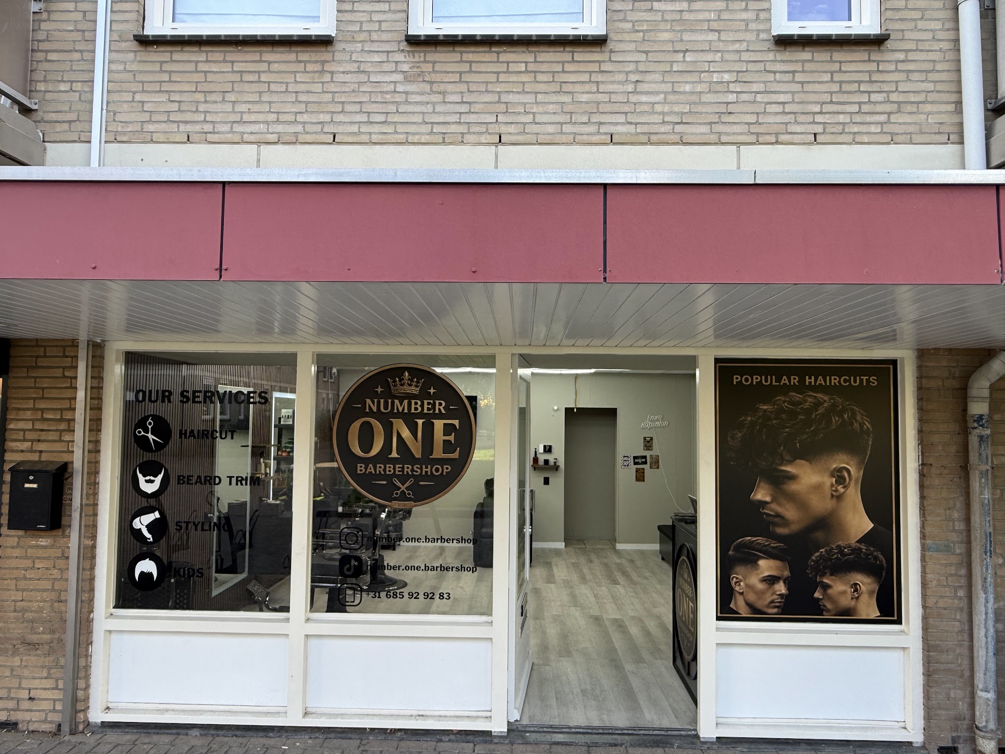 De etalage van Number one Barbershop met het ronde logo op het raam